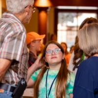student talking to adults in front of posters from student project showcase